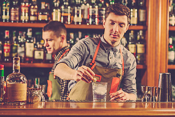 Image showing Expert barman is making cocktail at night club.