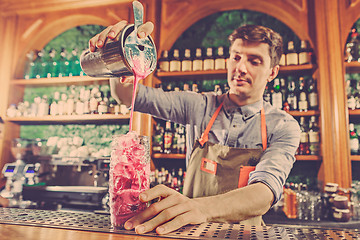 Image showing Expert barman is making cocktail at night club.