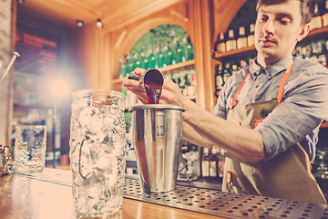 Image showing Expert barman is making cocktail at night club.