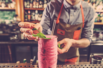 Image showing Expert barman is making cocktail at night club.