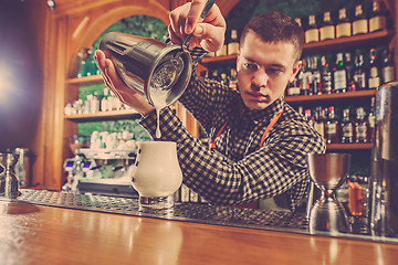 Image showing Barman making an alcoholic cocktail at the bar counter on the bar background