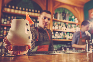 Image showing Barman offering an alcoholic cocktail at the bar counter on the bar background