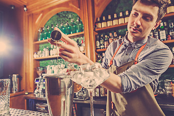 Image showing Expert barman is making cocktail at night club.