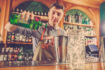 Image showing Expert barman is making cocktail at night club.