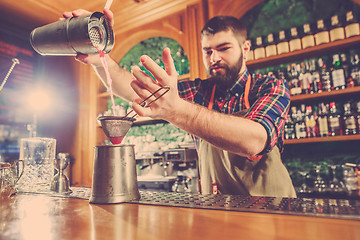 Image showing Barman making an alcoholic cocktail at the bar counter on the bar background