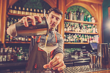 Image showing Expert barman is making cocktail at night club.