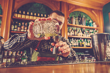 Image showing Barman making an alcoholic cocktail at the bar counter on the bar background