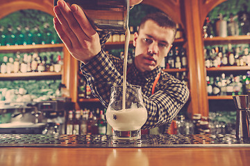 Image showing Barman making an alcoholic cocktail at the bar counter on the bar background