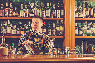 Image showing Barman making an alcoholic cocktail at the bar counter on the bar background