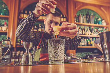 Image showing Barman making an alcoholic cocktail at the bar counter on the bar background