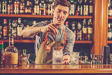 Image showing Expert barman is making cocktail at night club.