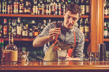 Image showing Expert barman is making cocktail at night club.