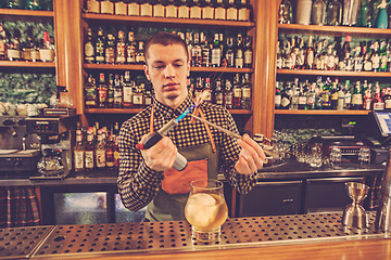 Image showing Barman making an alcoholic cocktail at the bar counter on the bar background