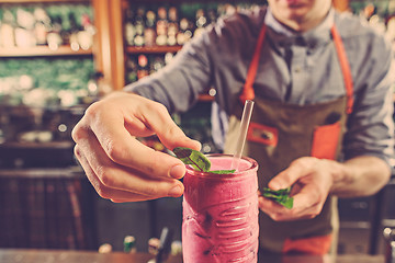 Image showing Expert barman is making cocktail at night club.