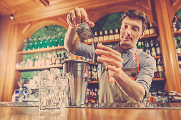 Image showing Expert barman is making cocktail at night club.