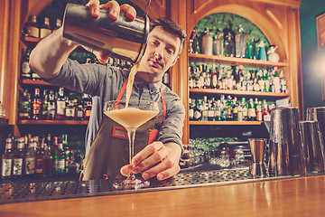 Image showing Expert barman is making cocktail at night club.