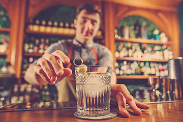 Image showing Expert barman is making cocktail at night club.