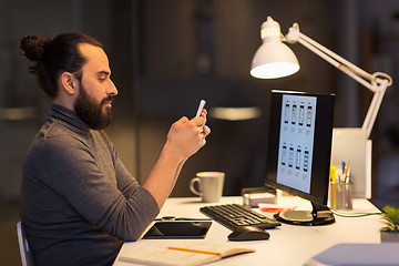 Image showing creative man with smartphone at night office