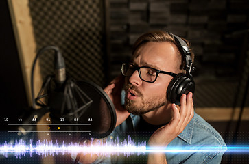 Image showing man with headphones singing at recording studio