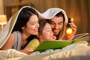 Image showing happy family reading book in bed at night at home