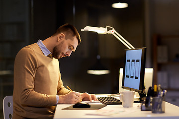 Image showing man with notepad working at night office