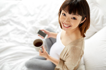 Image showing happy pregnant woman with cup of tea in bed