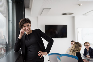 Image showing Elegant Woman Using Mobile Phone by window in office building