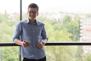 Image showing Businessman Standing In A Modern Building Near The Window With P