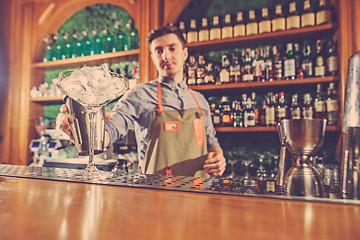 Image showing Expert barman is making cocktail at night club.