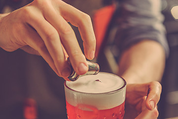 Image showing Barman making an alcoholic cocktail at the bar counter on the bar background