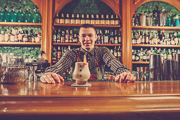 Image showing Barman offering an alcoholic cocktail at the bar counter on the bar background