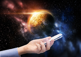 Image showing hand holding smartphone over planet in space