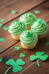 Image showing green cupcakes with shamrock decorations on table