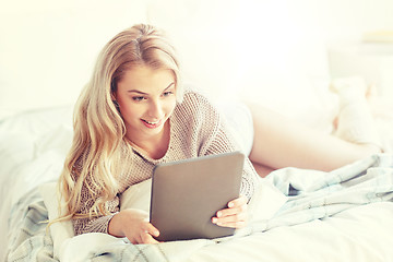 Image showing happy young woman with tablet pc in bed at home