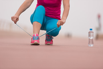 Image showing Young woman tying shoelaces on sneakers