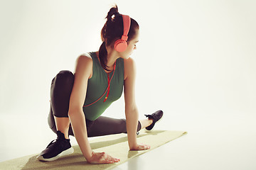 Image showing Front view of a young woman stretching body in gymnastics class.