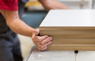 Image showing close up of carpenter with boards at factory