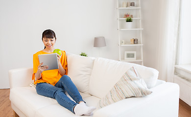 Image showing happy asian woman with tablet pc and apple at home