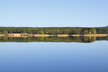 Image showing Lake with forest line mirrored in calm water surface