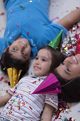 Image showing kids  blowing confetti while lying on the floor