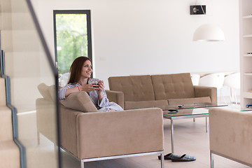 Image showing young woman in a bathrobe enjoying morning coffee