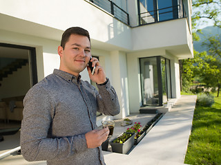 Image showing man using mobile phone in front of his luxury home villa
