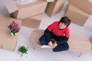 Image showing boy sitting on the table with cardboard boxes around him top vie