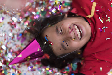 Image showing kid blowing confetti while lying on the floor