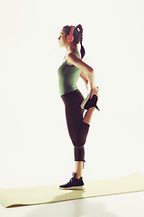 Image showing The side view of a young woman stretching body in gymnastics class.