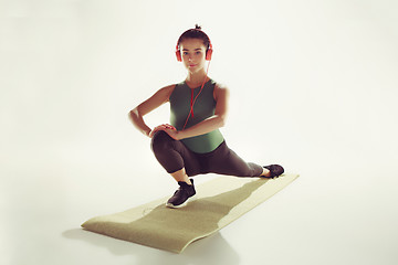 Image showing Front view of a young woman stretching body in gymnastics class.