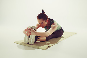 Image showing Beautiful slim brunette doing some stretching exercises in a gym