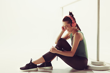 Image showing Front view of a young woman sitting with headphones