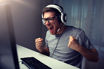 Image showing man in headset playing computer video game at home