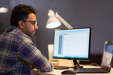 Image showing creative man working with laptop at night office